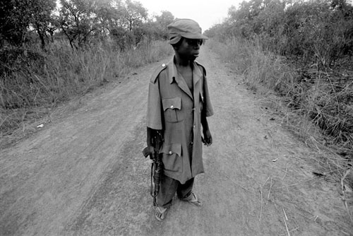 2004, Northern Uganda. Wearing an over-sized uniform and carrying a Kalashnikov, 12-year-old child soldier Omoding Musami patrols a dangerous stretch of the Obalanga Road. © Alixandra Fazzina